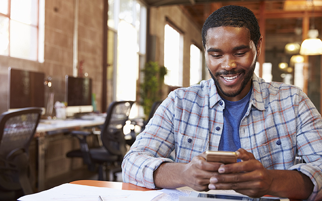 Designer Sitting At Meeting Table Texting On Mobile Phone