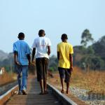 Young men walking along a railway line